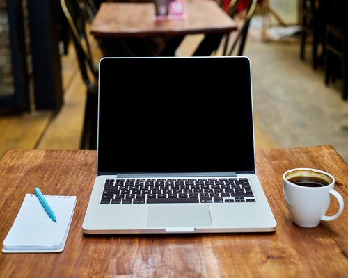A laptop screen showing notes next to a healthy workspace beverage
